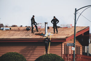 Three people standing on a broken roof.