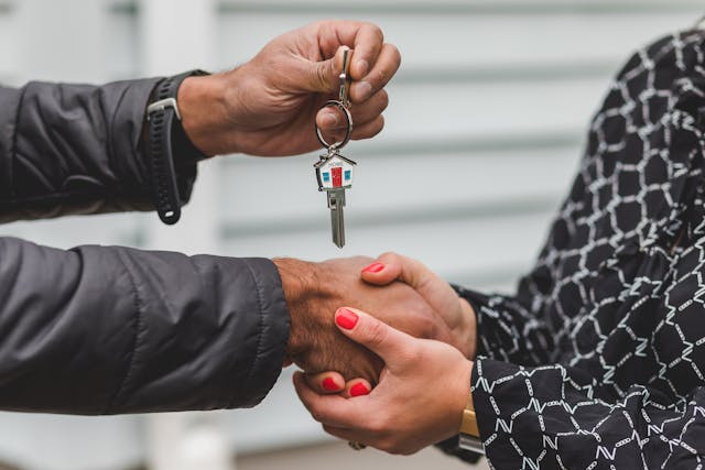 Close-up of one person handing over house keys to another during an owner-to-owner property transaction